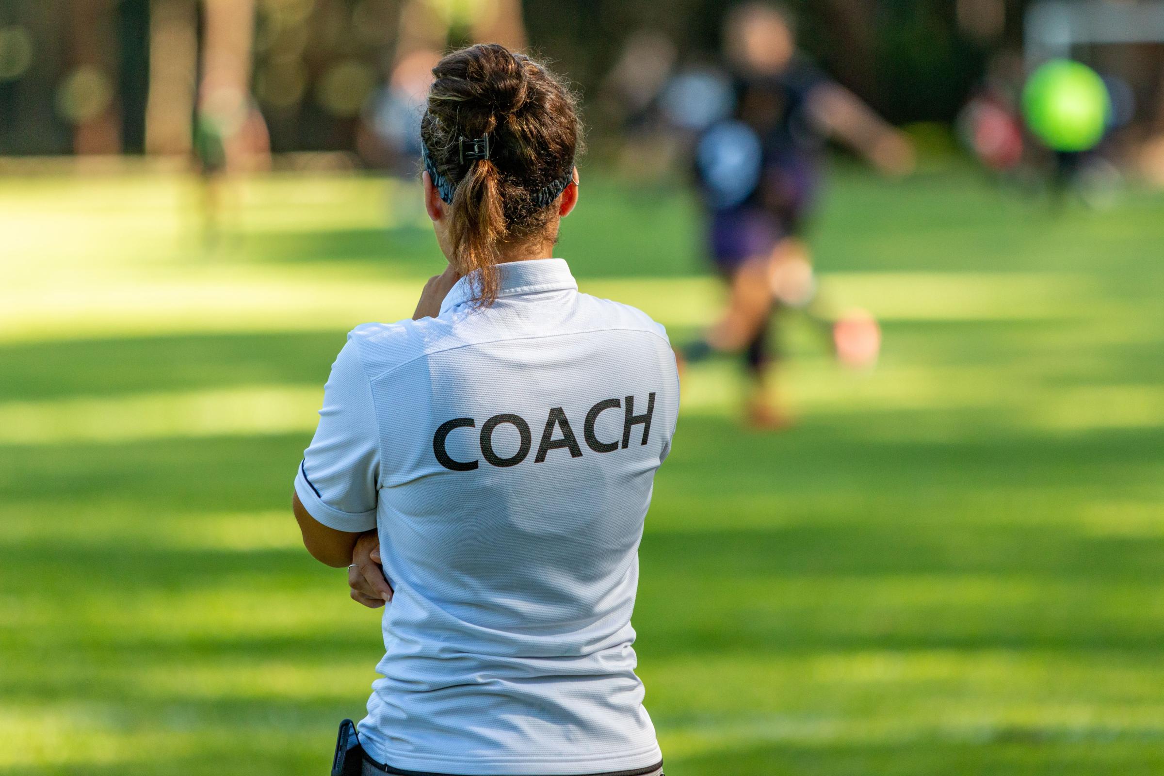 Woman wearing tshirt with 'coach' on the back, standing in a field