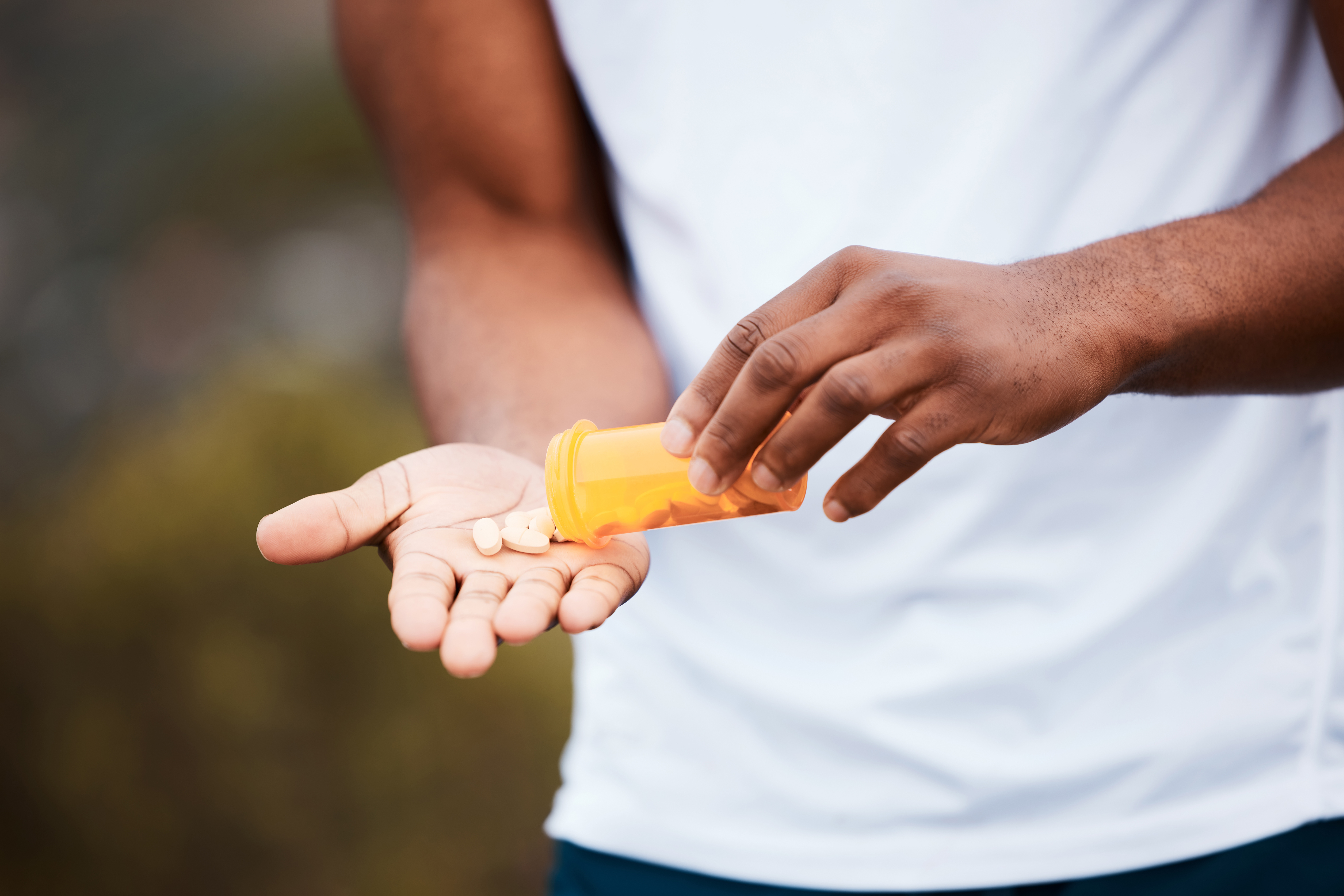 A person tipping tablet medication into their hand
